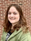 Katelyn smiling in front of a brick wall.